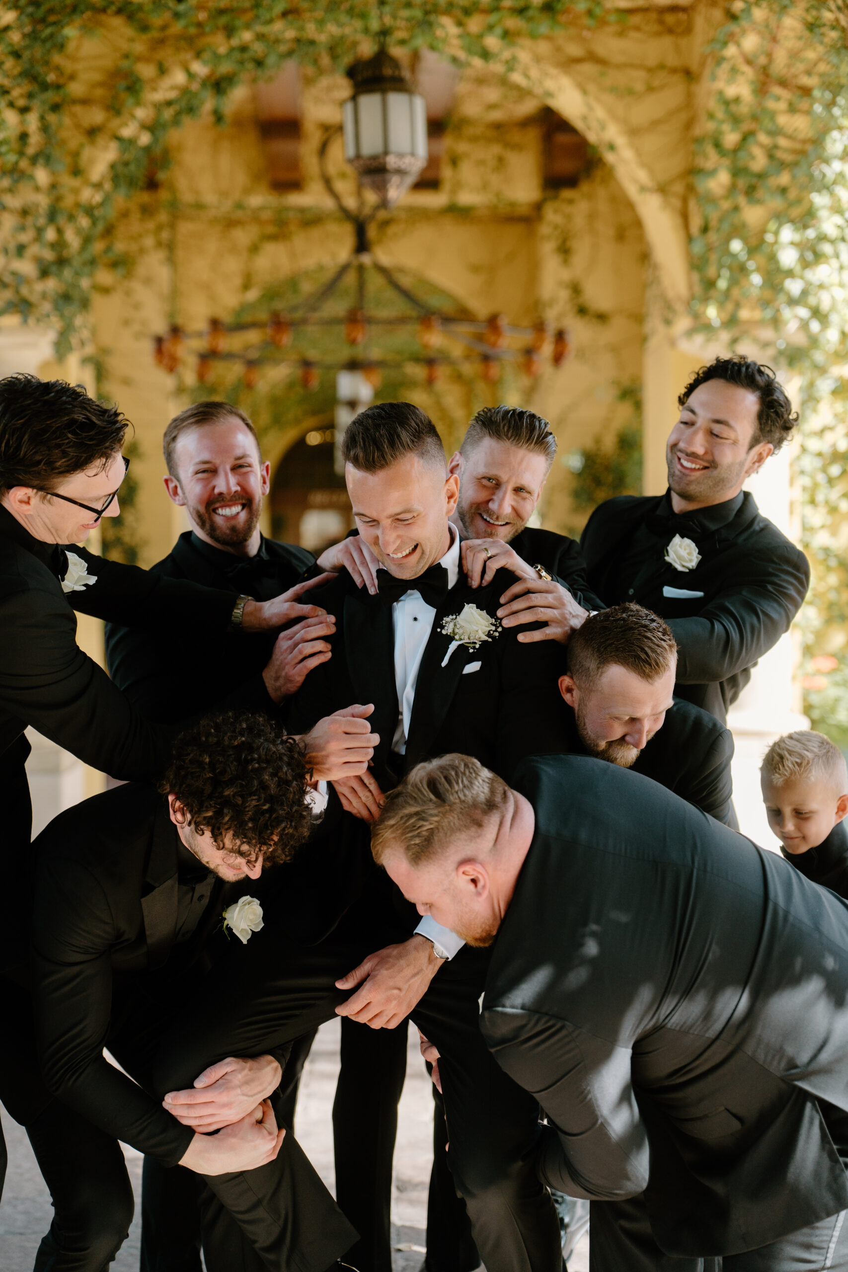 Groom laughing as his groomsmen playfully crowd around him before the ceremony at the Omni Montelucia.