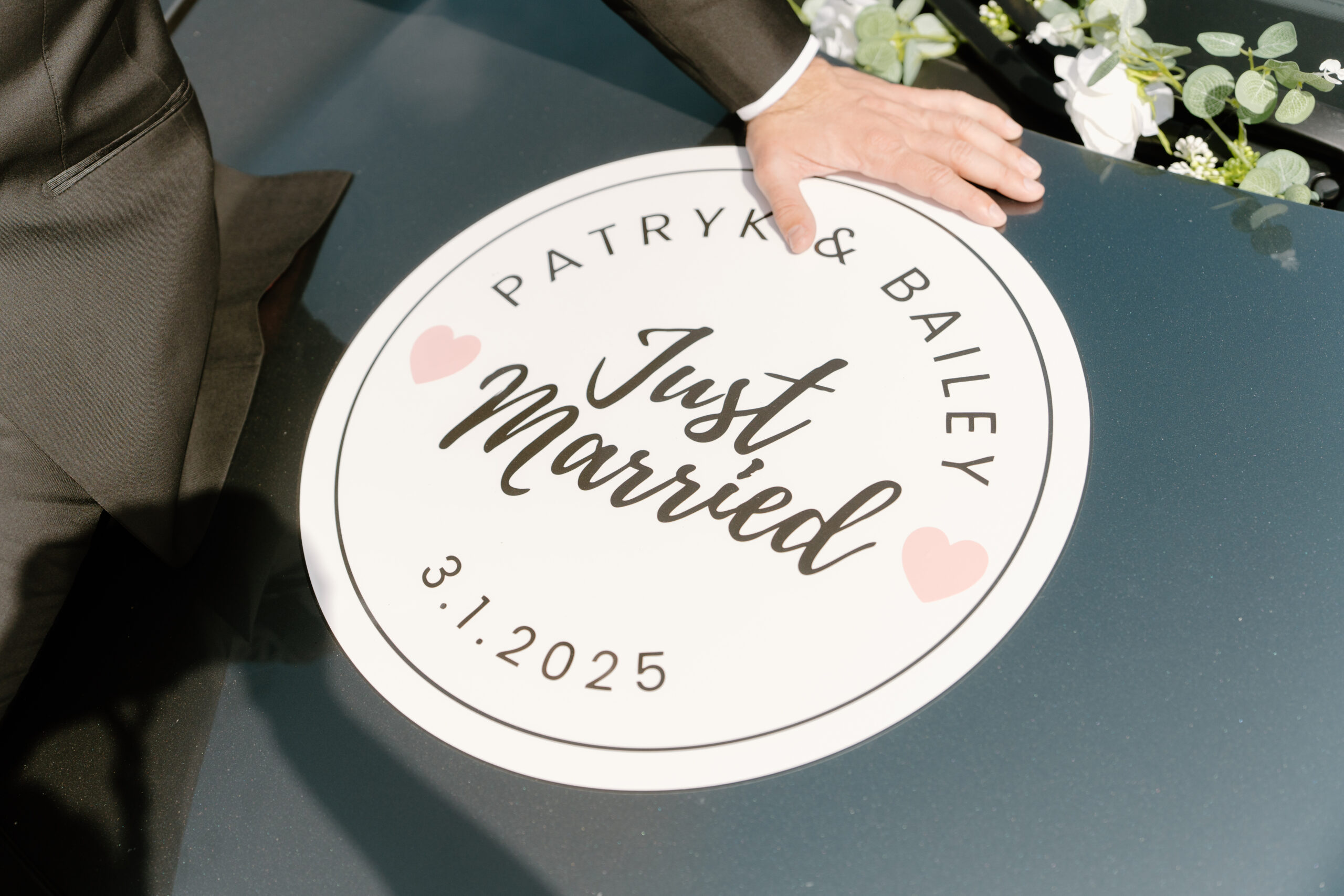 The groom rests his hand beside a “Just Married” decal on their getaway car at Omni Montelucia, marking the start of their new chapter.