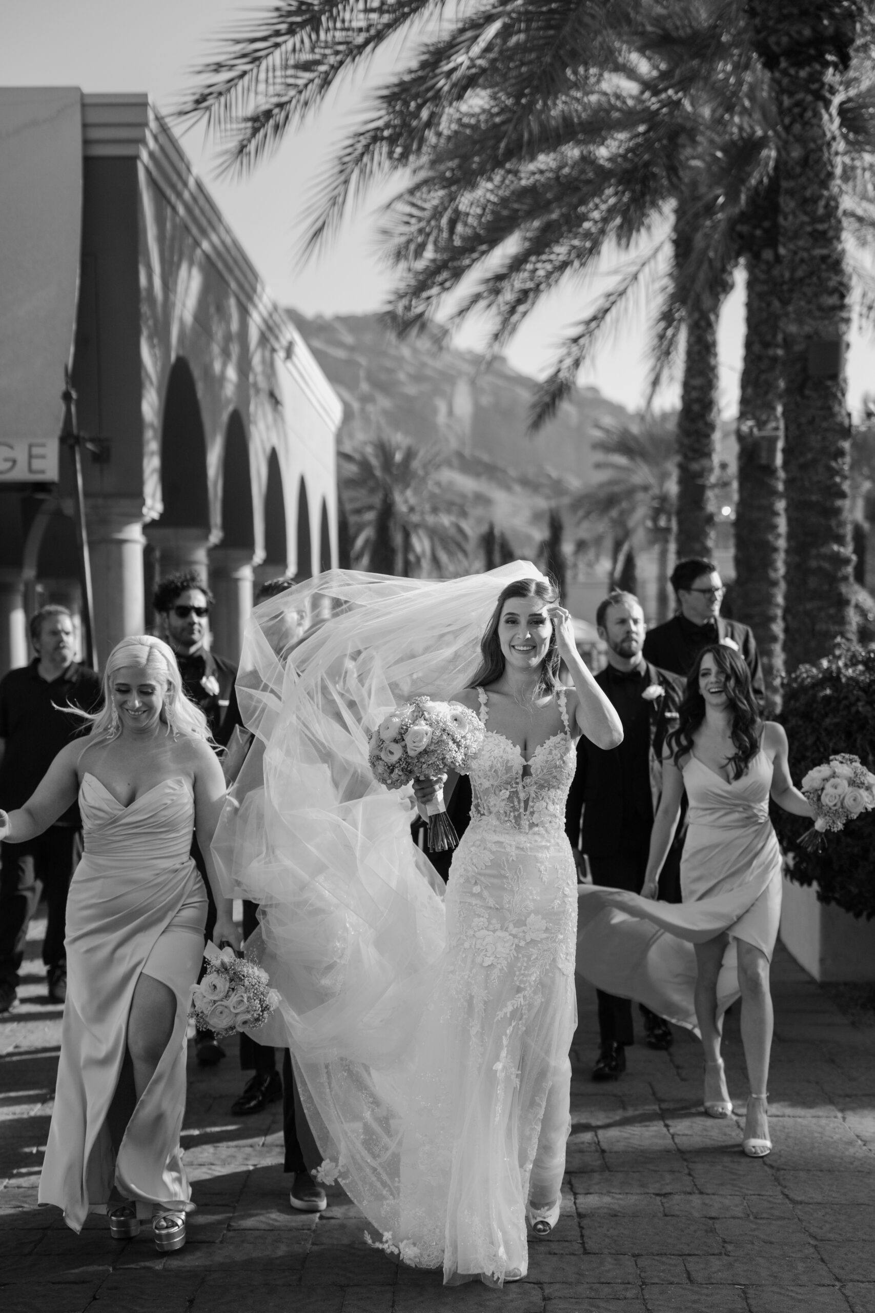 The bride walks through Omni Montelucia surrounded by her bridal party, her veil flowing in the Arizona breeze.