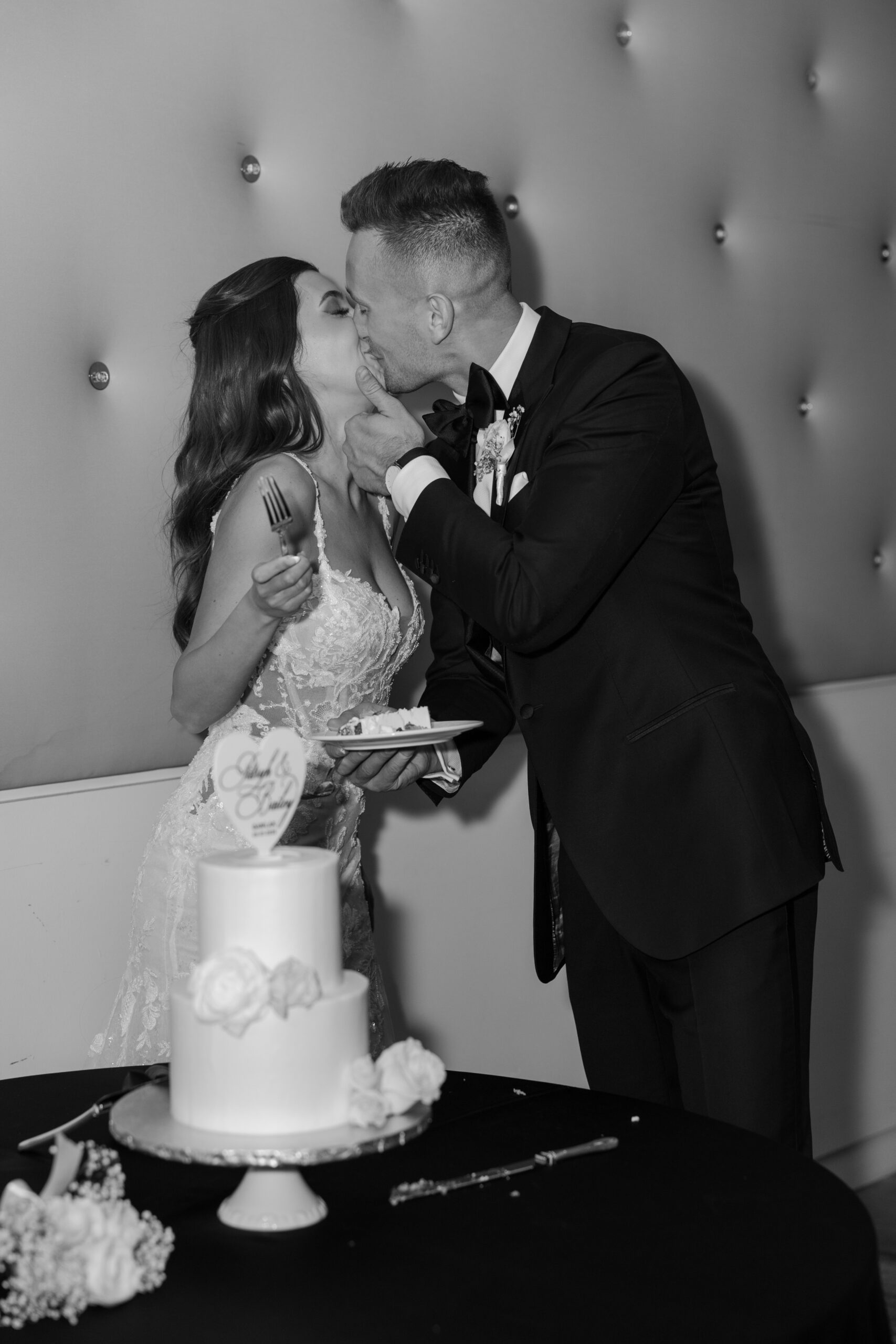 A joyful cake-cutting moment at the Omni Montelucia, where the bride and groom share a playful kiss between bites.