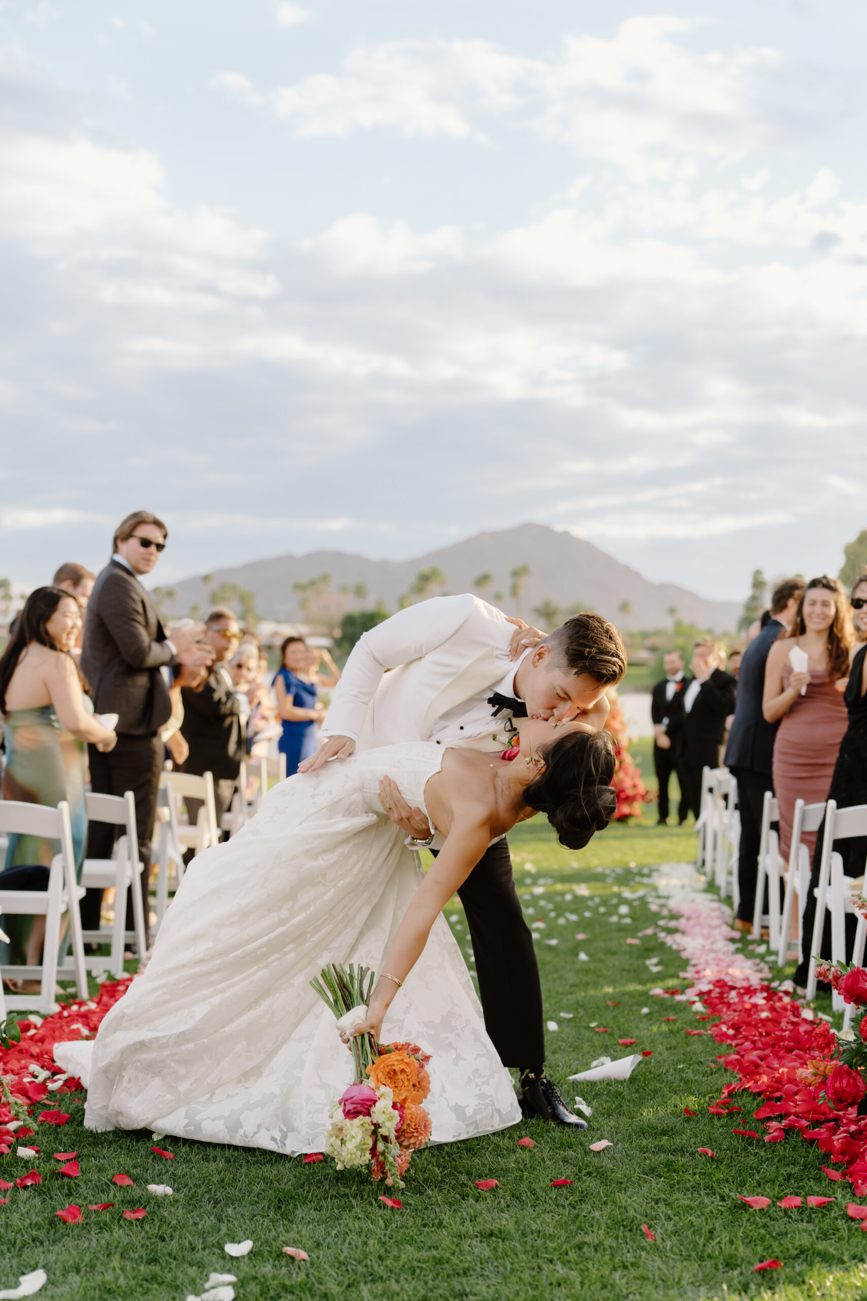 The groom dipping the bride for a kiss down the flower-lined ceremony aisle at mccormick ranch golf club.