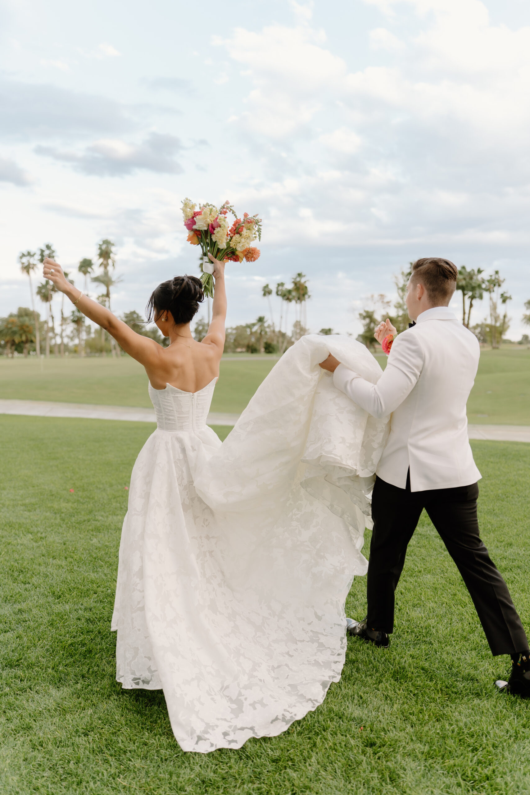 The couple walking away hand-in-hand, the bride lifting her bouquet as her dress flows behind her.