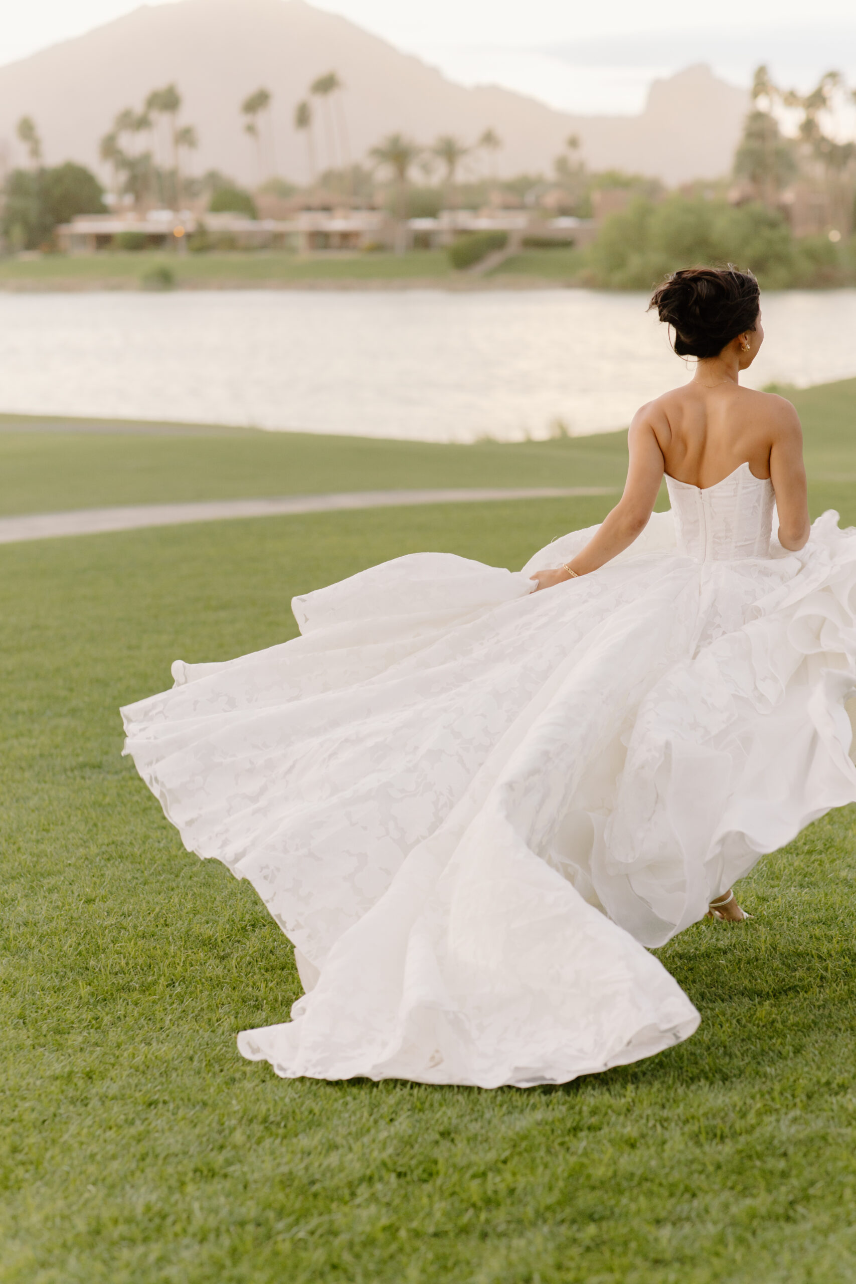 The bride twirling on the lawn, her full skirt billowing behind her with soft sunset light over the mountains.