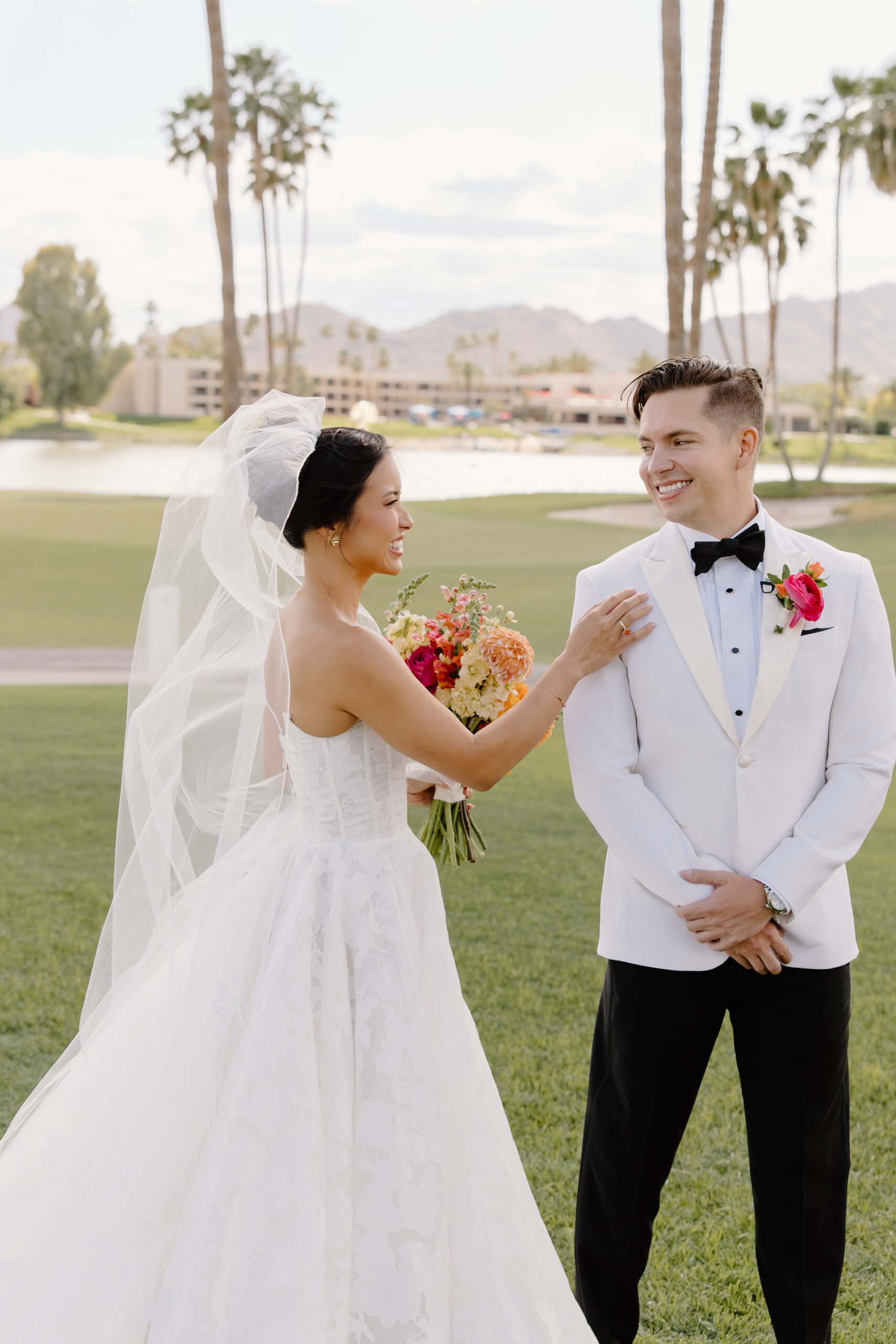 A playful first-look moment as the bride taps the groom’s shoulder, both smiling brightly at mccormick ranch golf club.