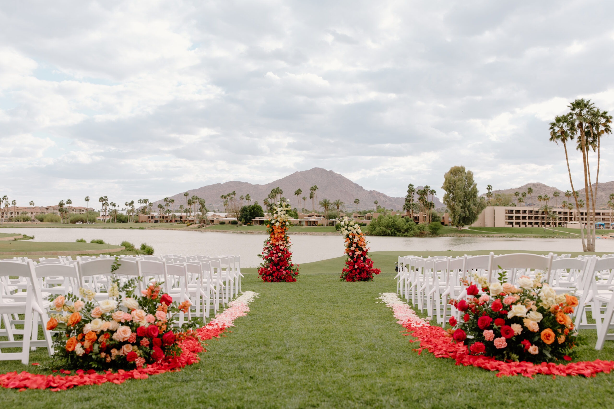 A ceremony aisle lined with bold floral arrangements, overlooking the lake and mountains at mccormick ranch golf club.