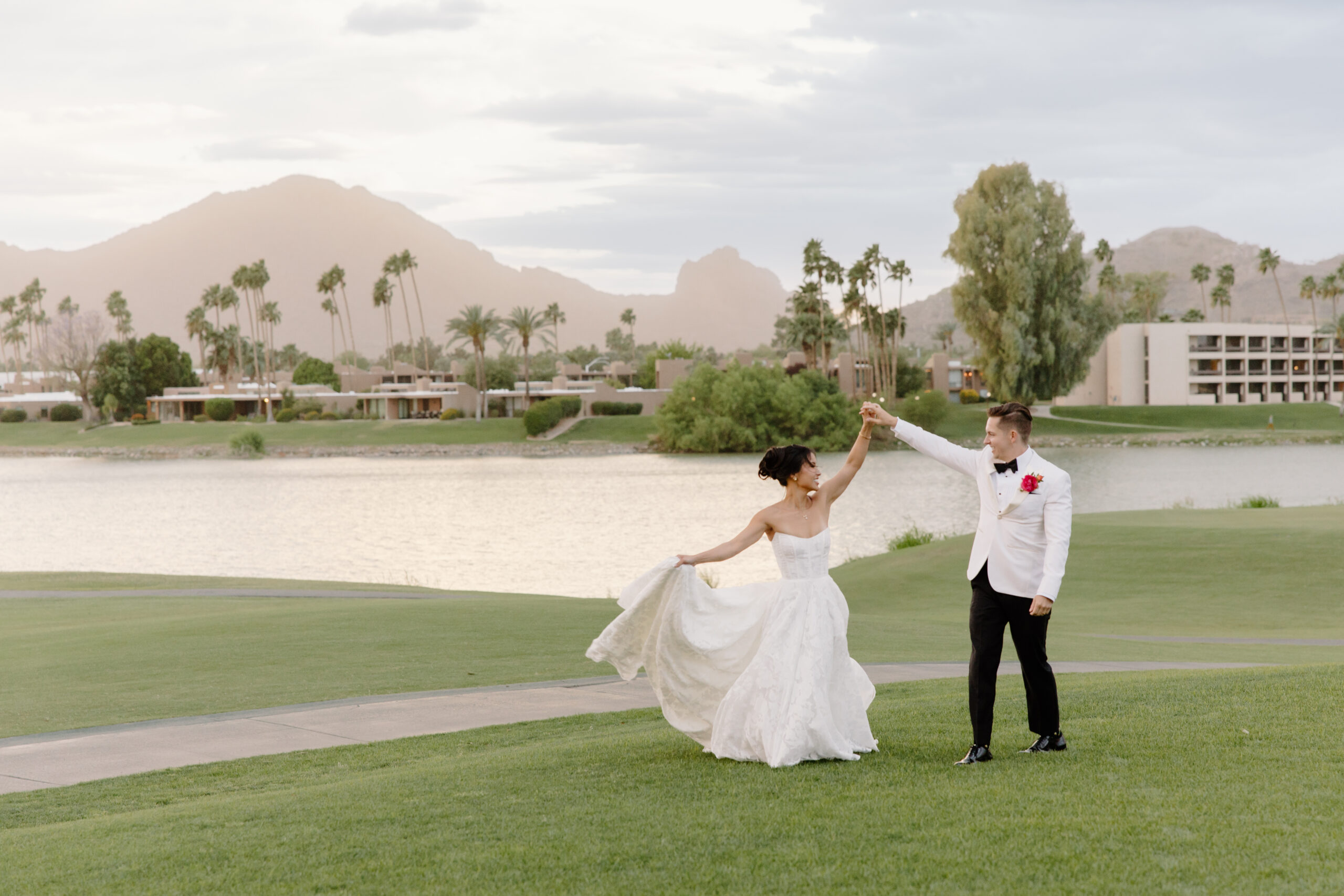 The couple dancing on the lawn at mccormick ranch golf club, framed by palm trees and mountains at sunset.