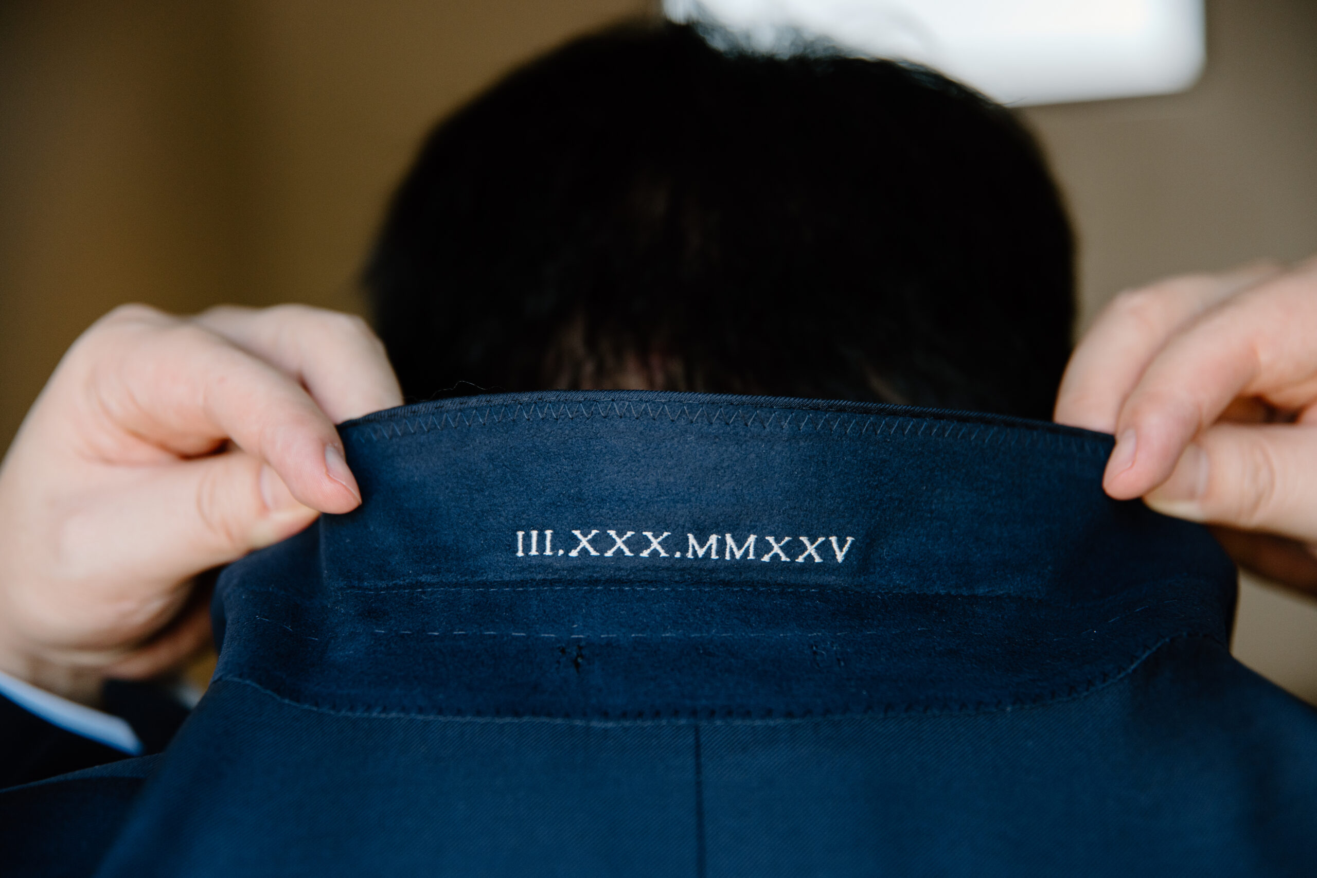 Close-up of the groom’s suit jacket from behind showing embroidered Roman numerals and the date stitched inside the collar at The Paseo, Arizona.