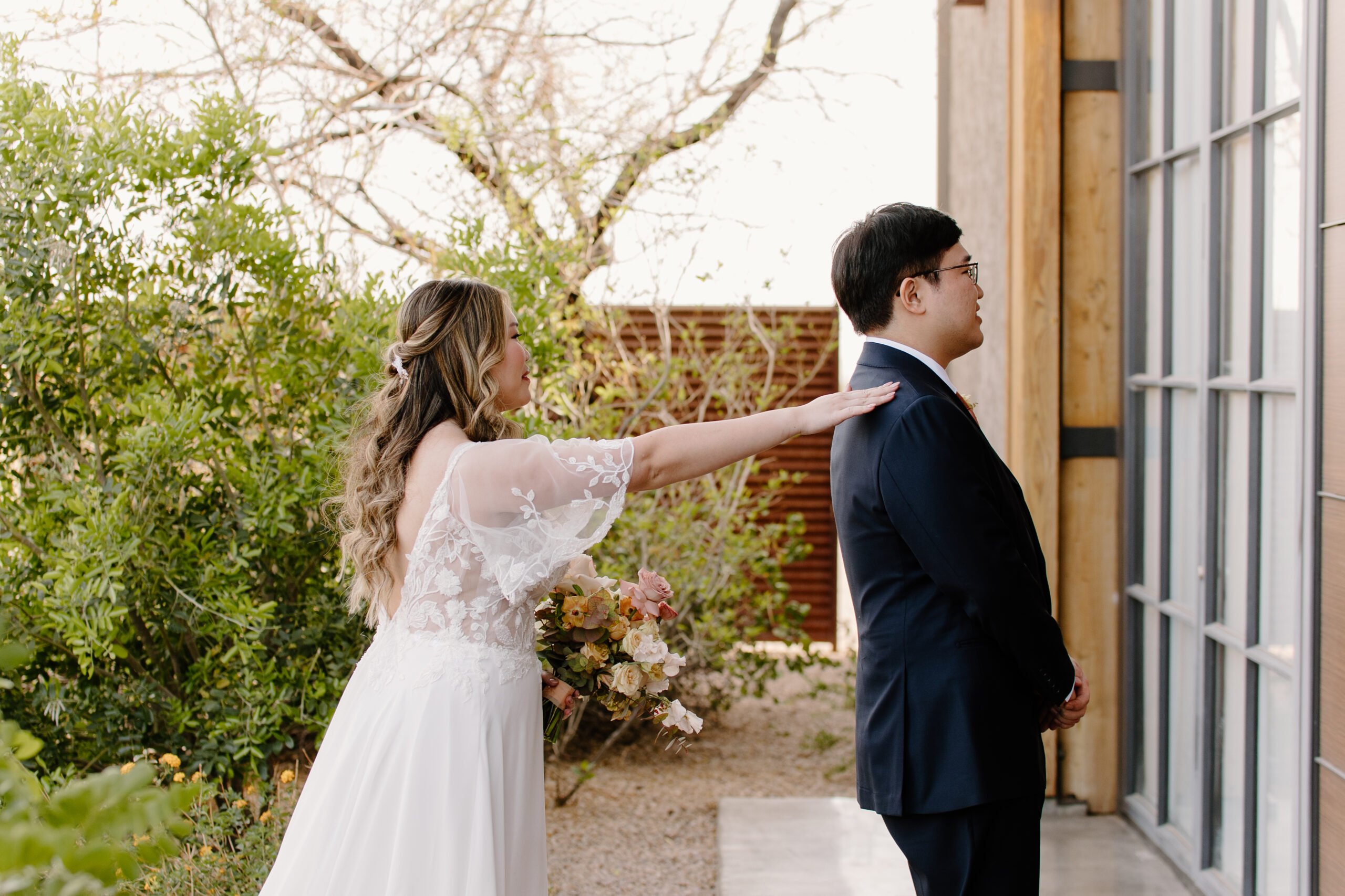 A first-look moment at The Paseo, Arizona, where the bride gently touches the groom’s shoulder before he turns around to see her.