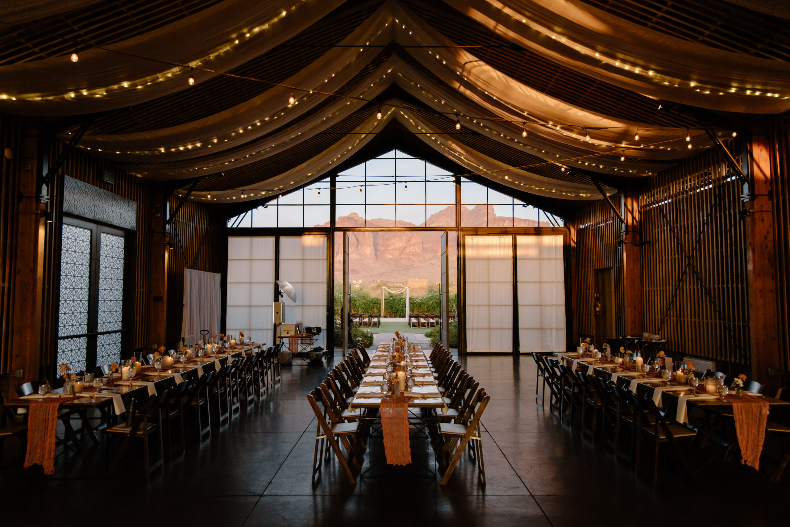 Wedding reception table set with candles and floral centerpieces inside a modern barn-style venue at The Paseo, Arizona.