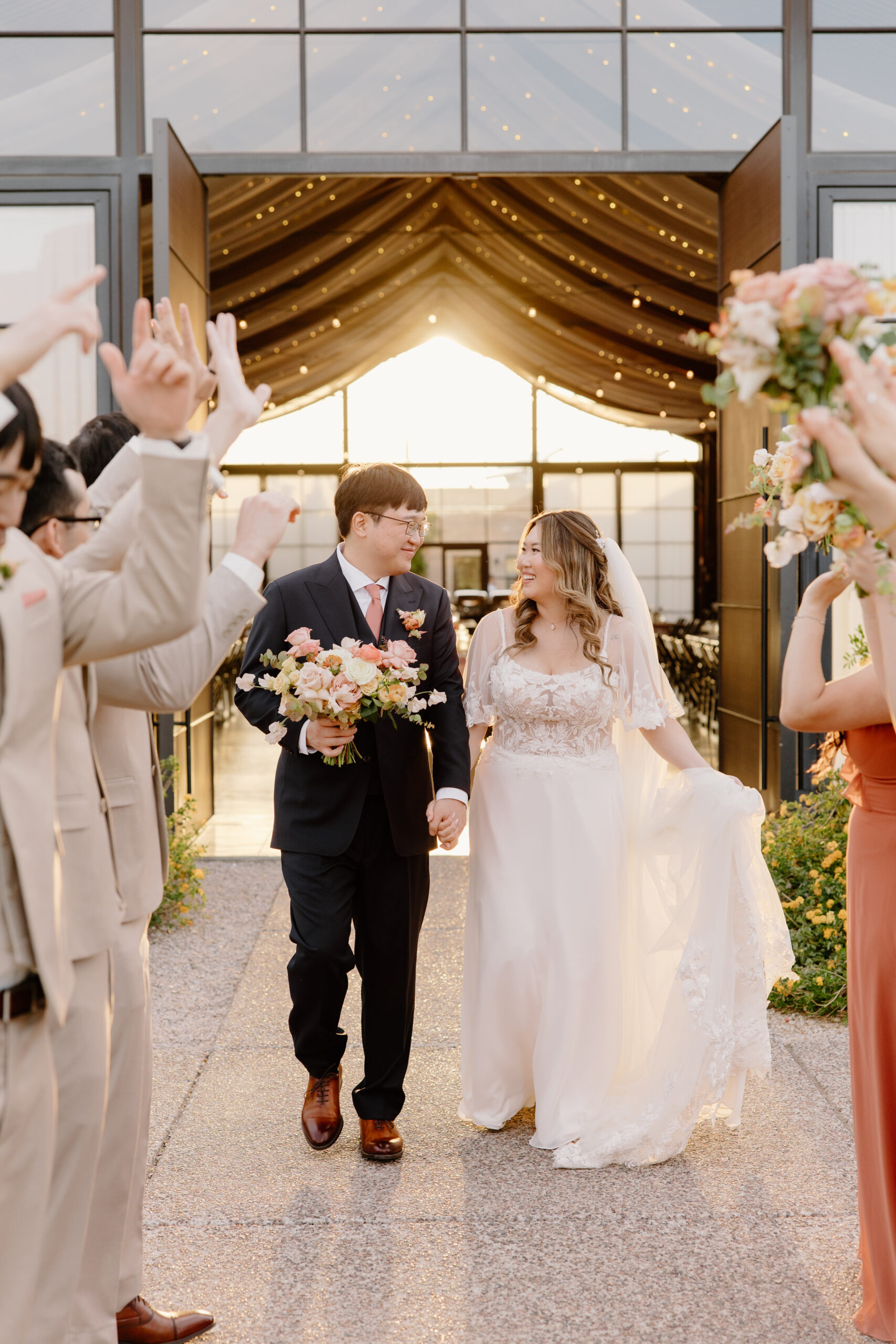 Guests cheering for the newlyweds during a celebratory recessional moment filled with smiles and movement.