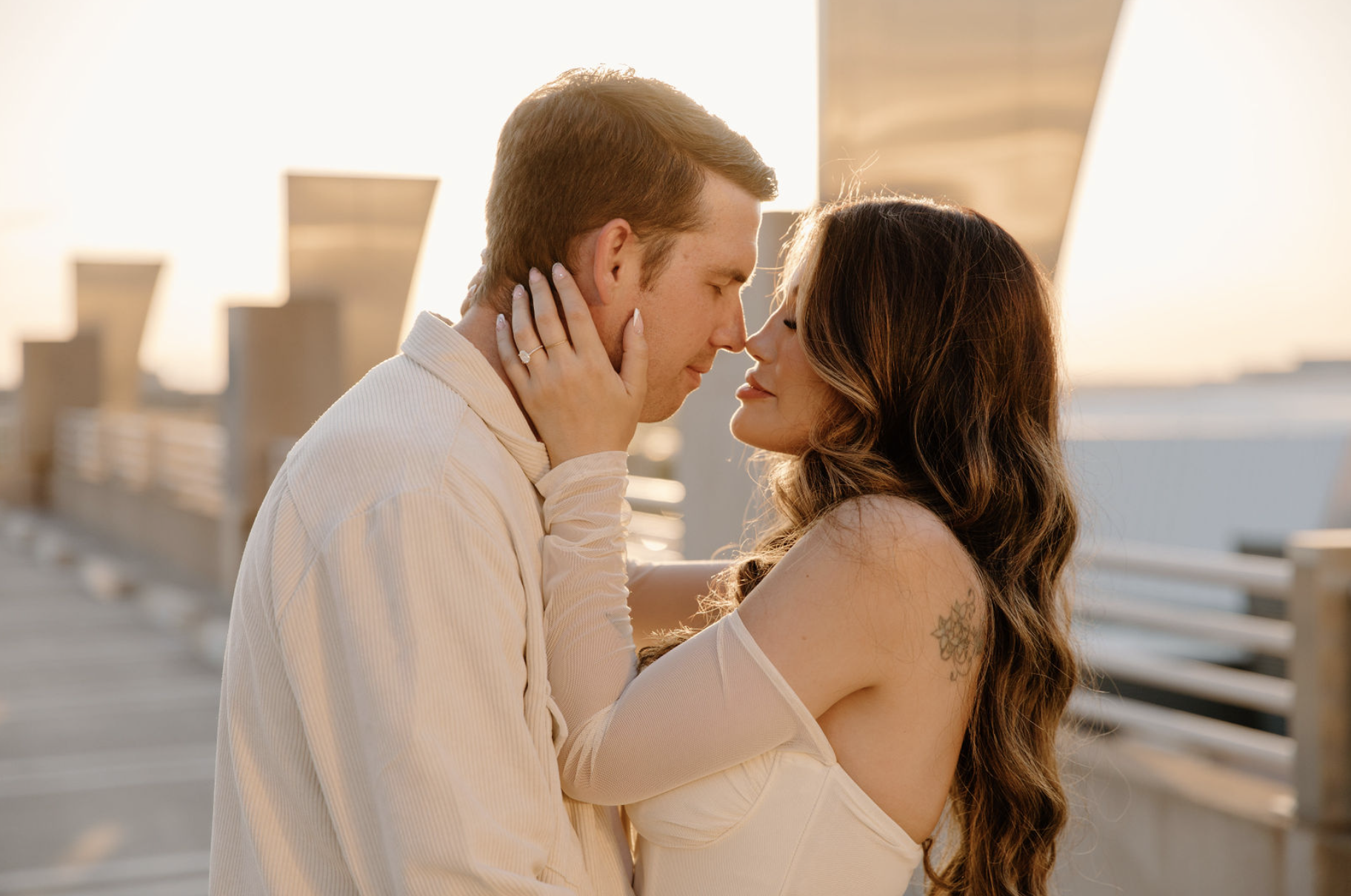 Close-up of a couple about to kiss on a rooftop at sunset, warm light glowing around them in an urban Arizona setting.