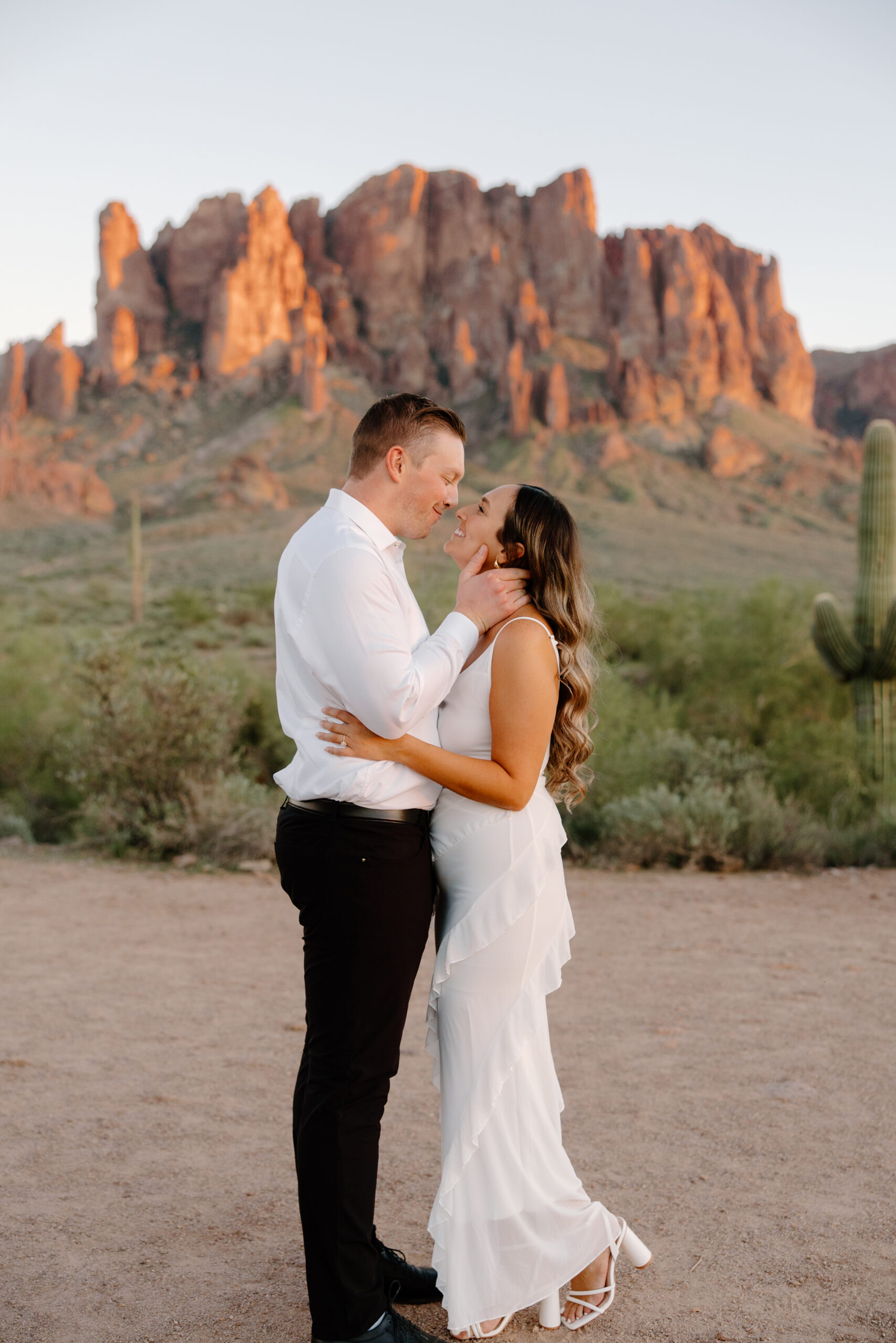 Close-up of couple embracing with glowing red rock cliffs in the background at sunset, capturing a timeless and emotional moment at one of the most iconic Arizona proposal locations.