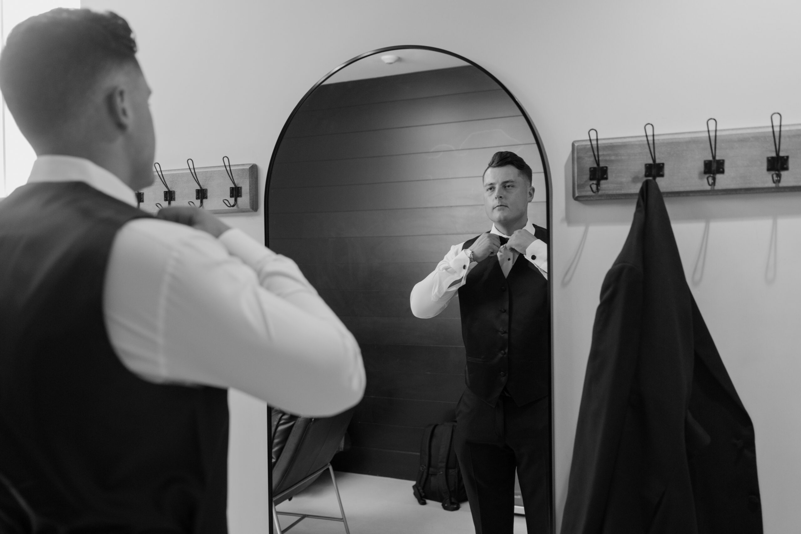 Groom adjusting his bow tie in a mirror while finishing getting ready for the Desert View wedding ceremony.