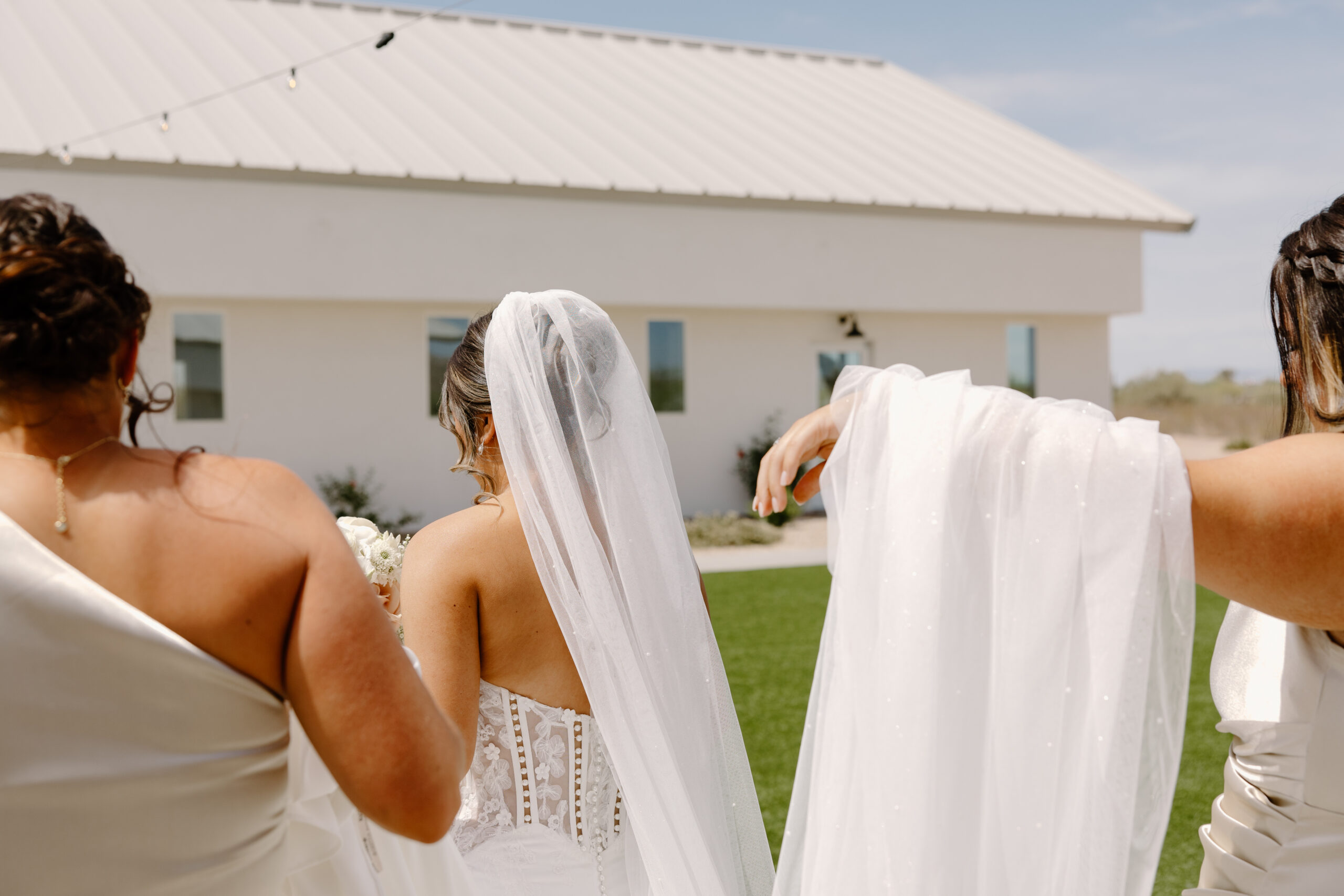 Bridesmaids adjusting the bride’s veil outdoors in front of the chapel before the ceremony at a Desert View wedding venue.