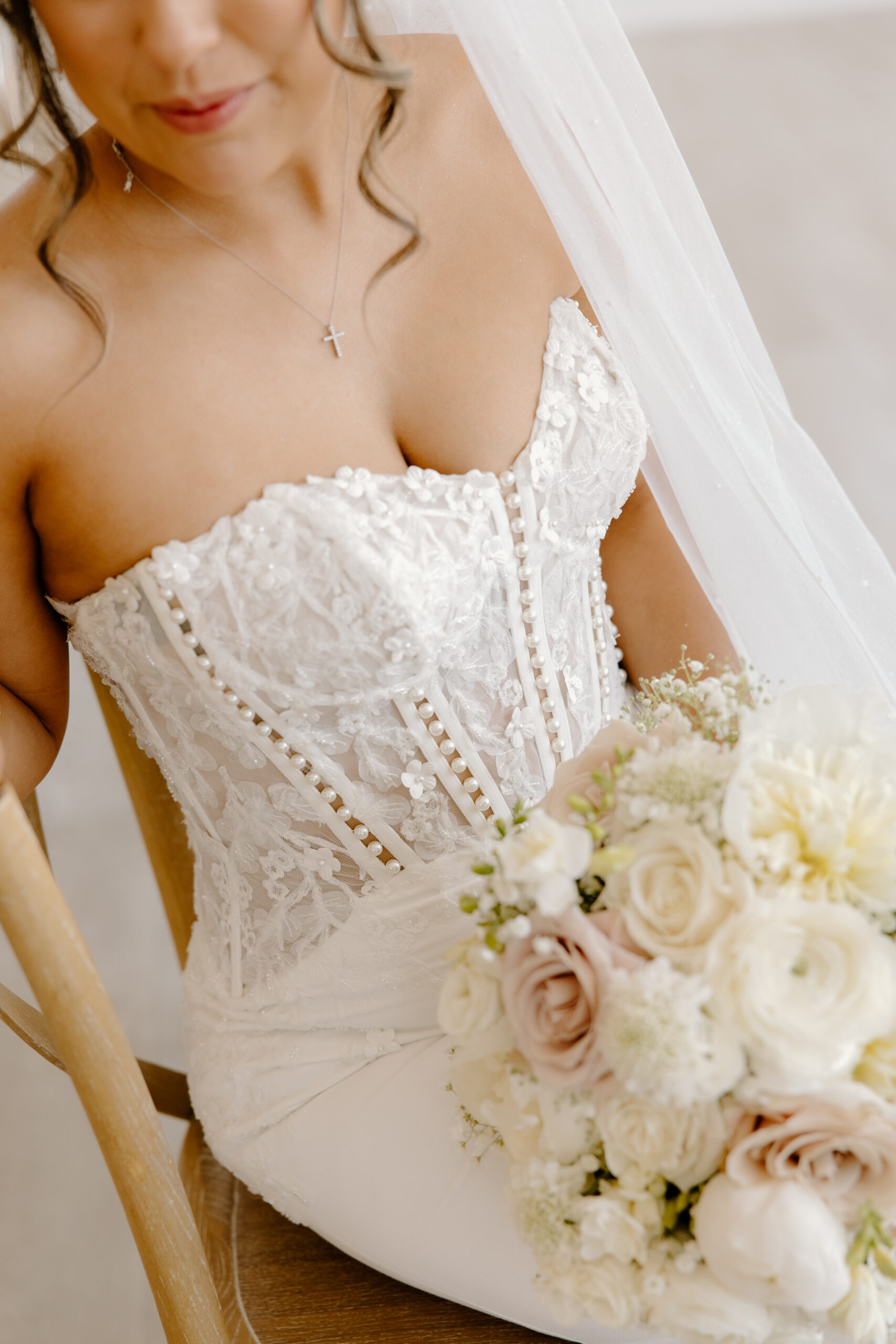 Close-up of a bride wearing a lace corset wedding dress holding a soft white and blush rose bouquet during her Desert View wedding.