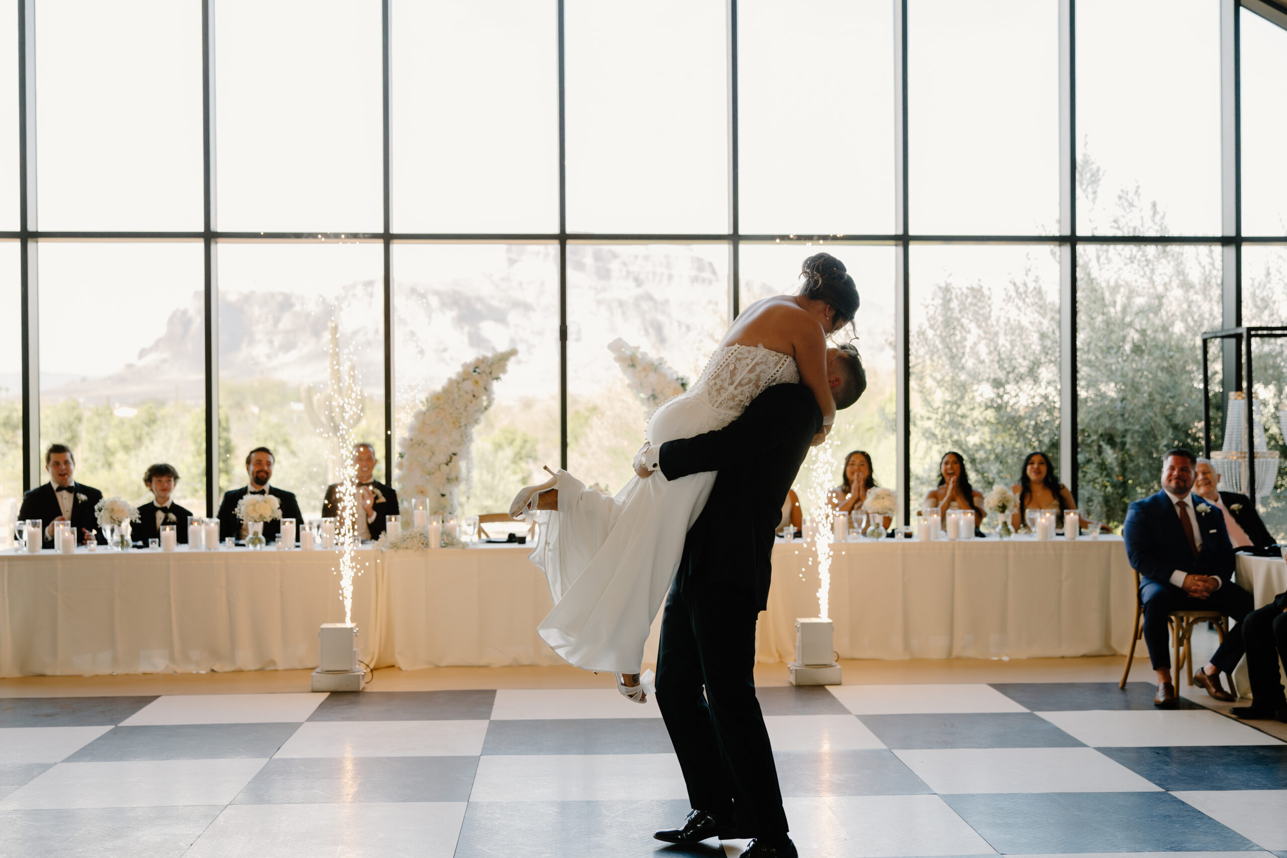 Groom lifting the bride during their first dance while guests watch and sparklers light up the dance floor at a Desert View wedding.