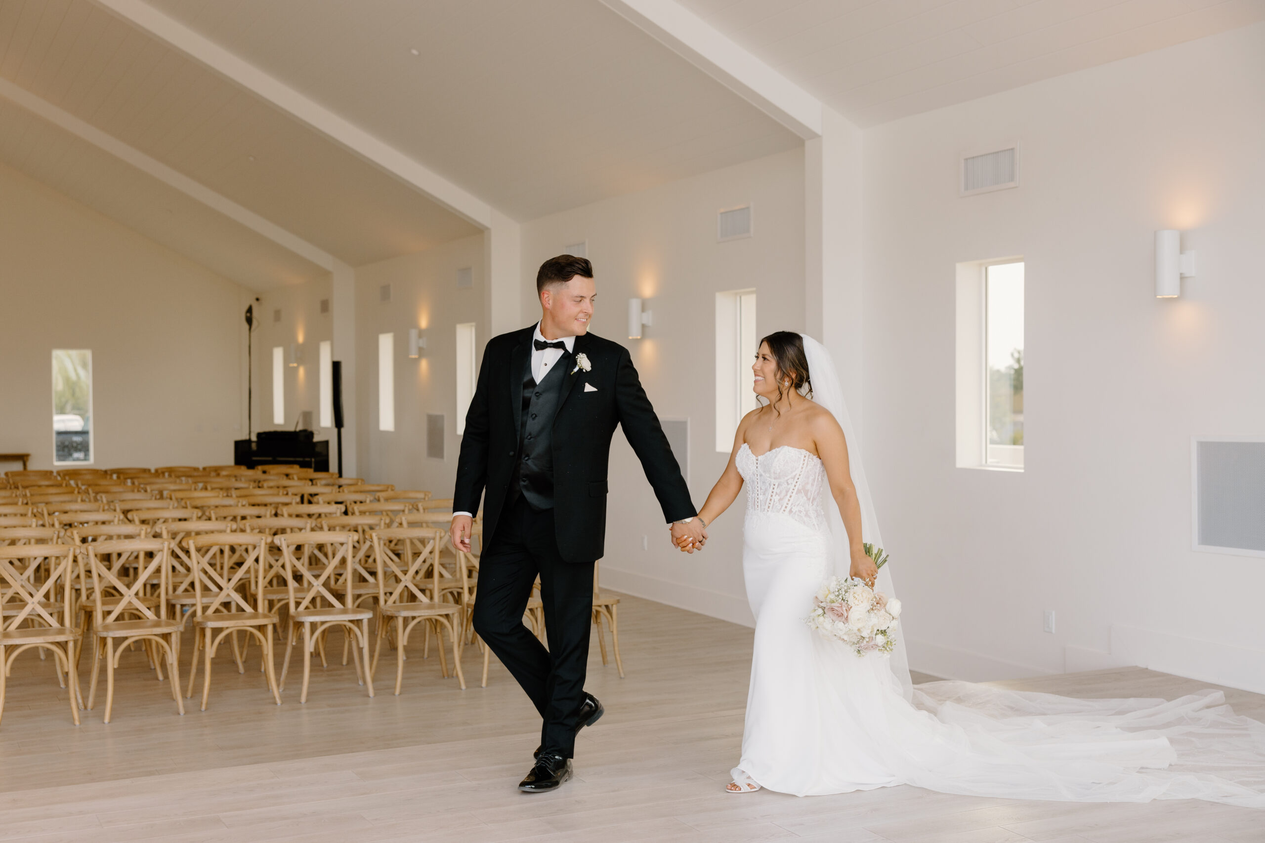 Newly married couple walking hand-in-hand through the chapel aisle after their ceremony.