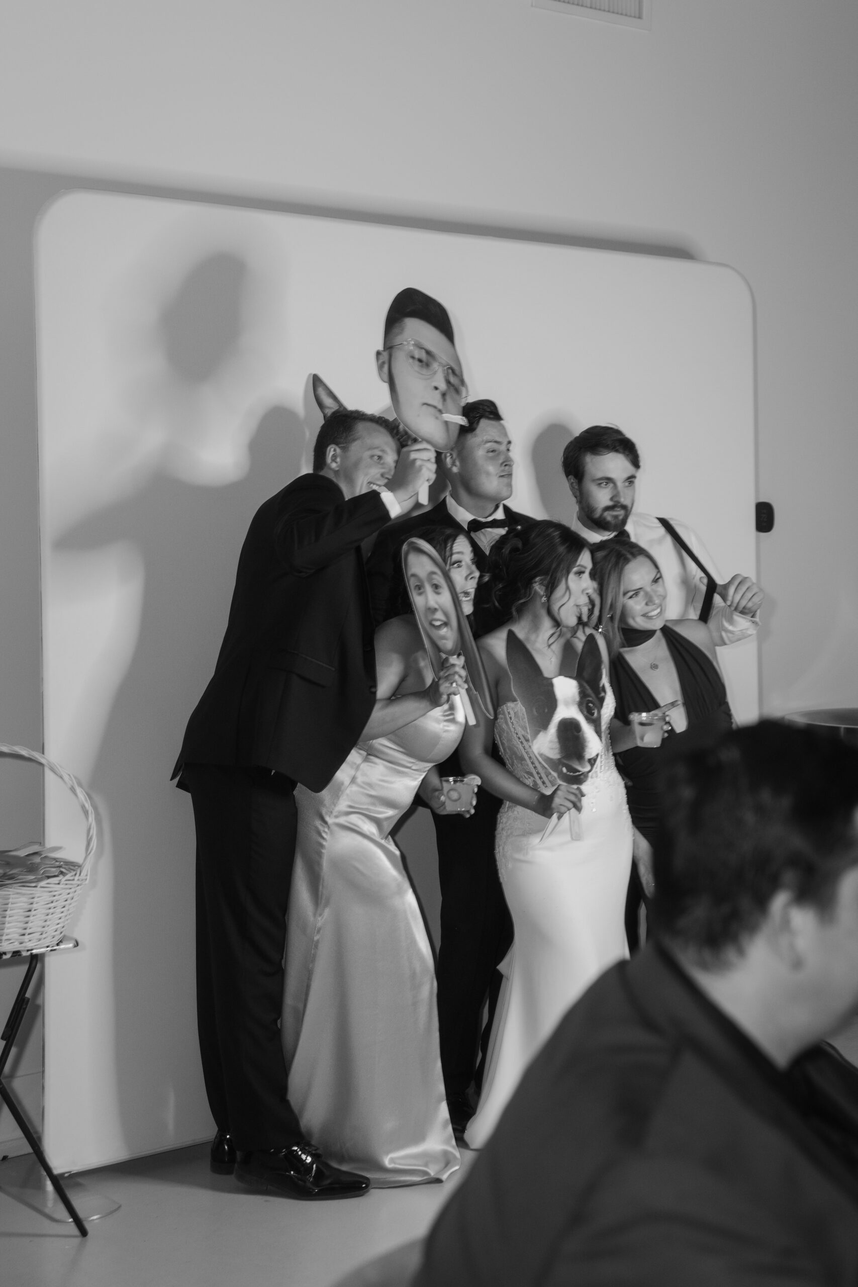 Bride, groom, and friends posing in a photo booth holding playful cutout props during the Desert View wedding reception.
