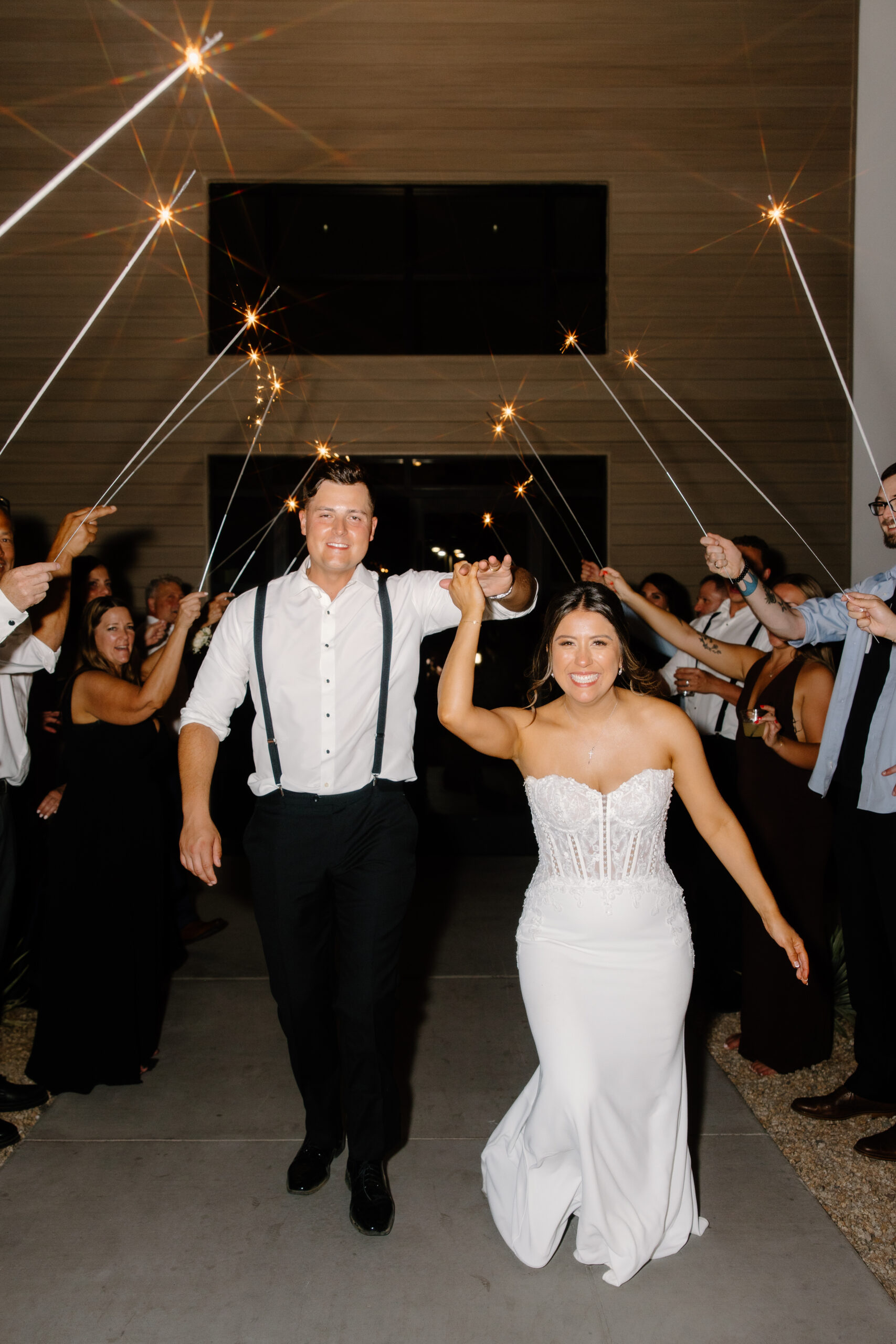 Bride and groom running through a tunnel of sparklers held by guests during their nighttime Desert View wedding exit.