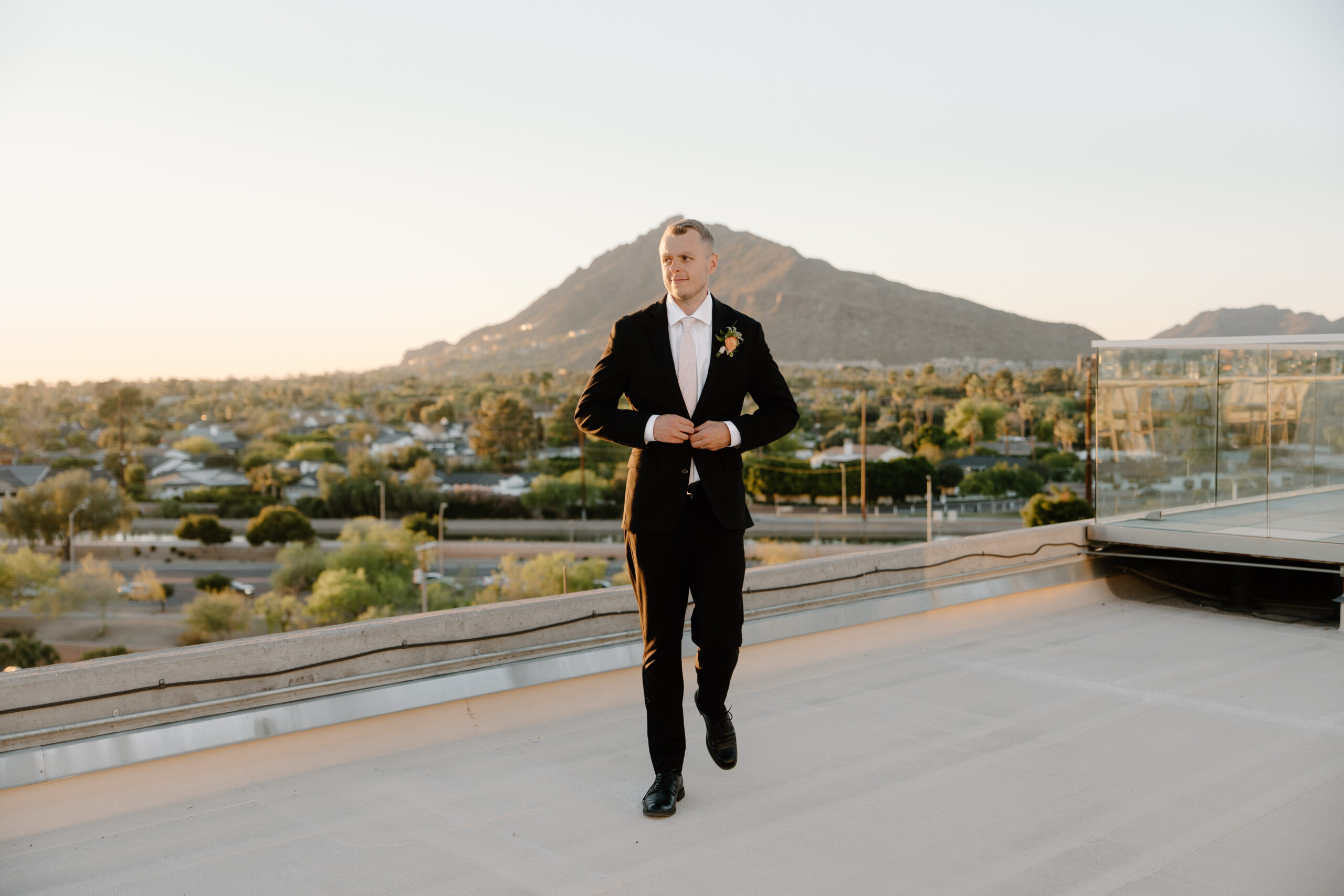 Groom walking across a rooftop at sunset with mountain views in the background at Hotel Valley Ho