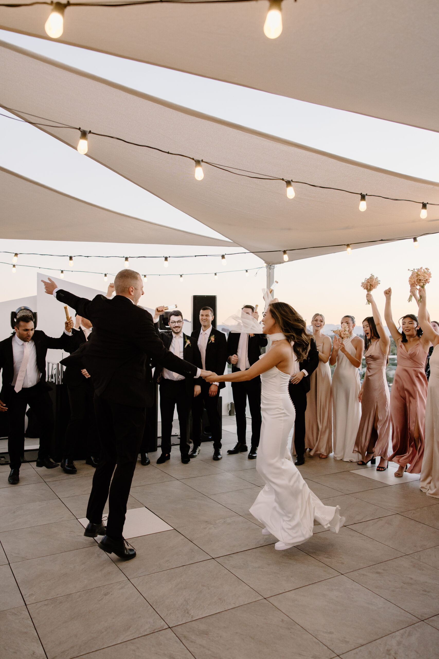 Bride and groom spinning on the dance floor during a lively reception with guests cheering around them
