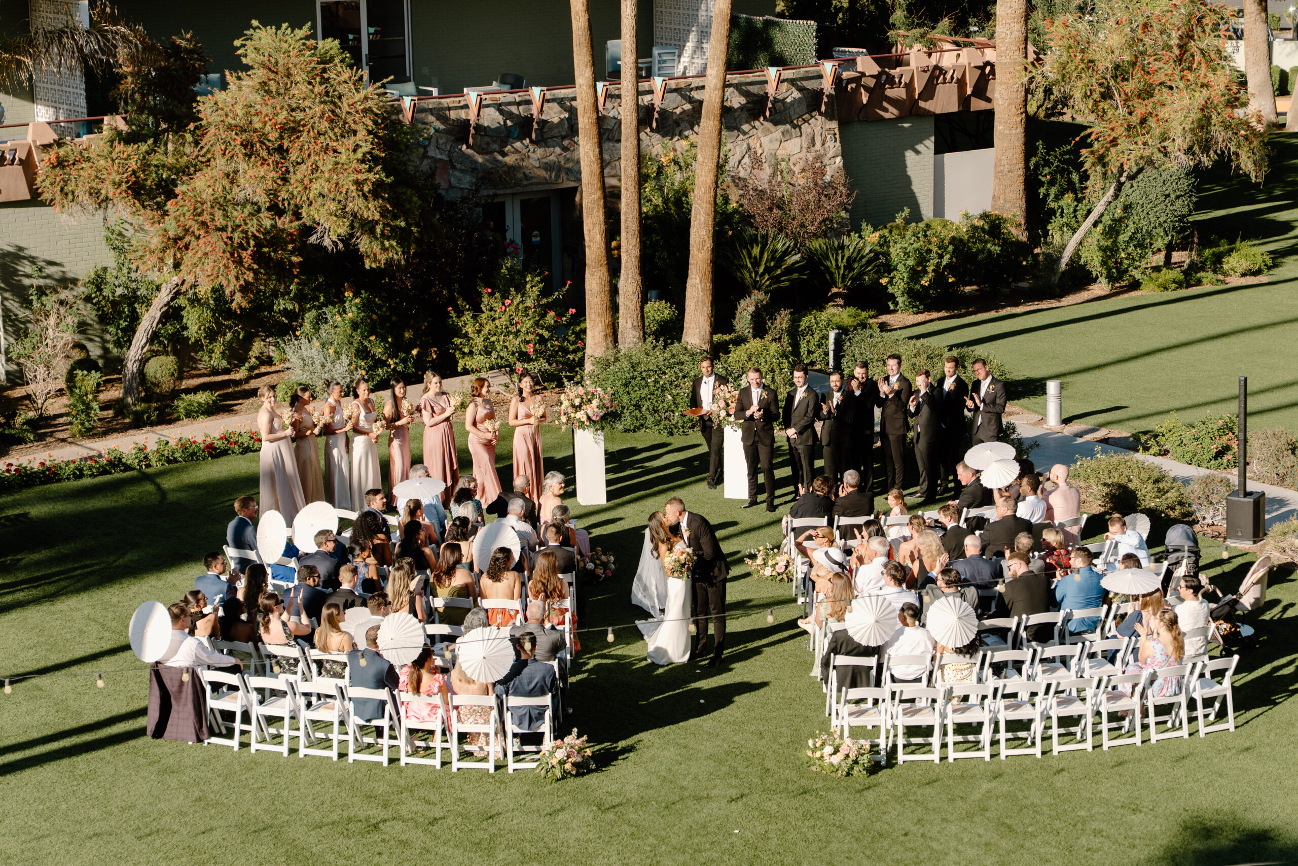 Outdoor wedding ceremony at Hotel Valley Ho with guests seated on white chairs and the couple sharing a kiss at the altar