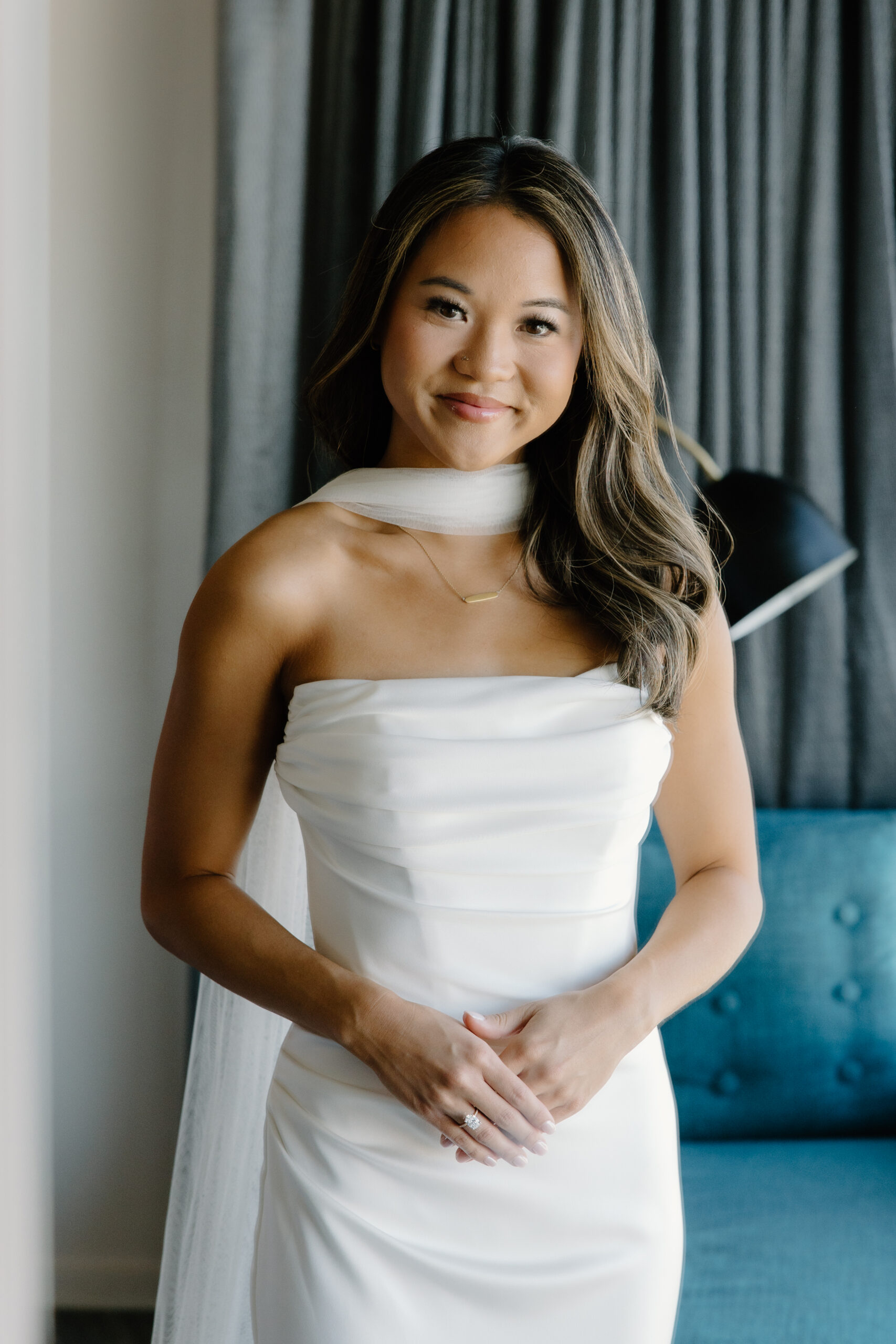 Bride smiling in a modern hotel suite, wearing a strapless gown with a soft scarf detail at Hotel Valley Ho