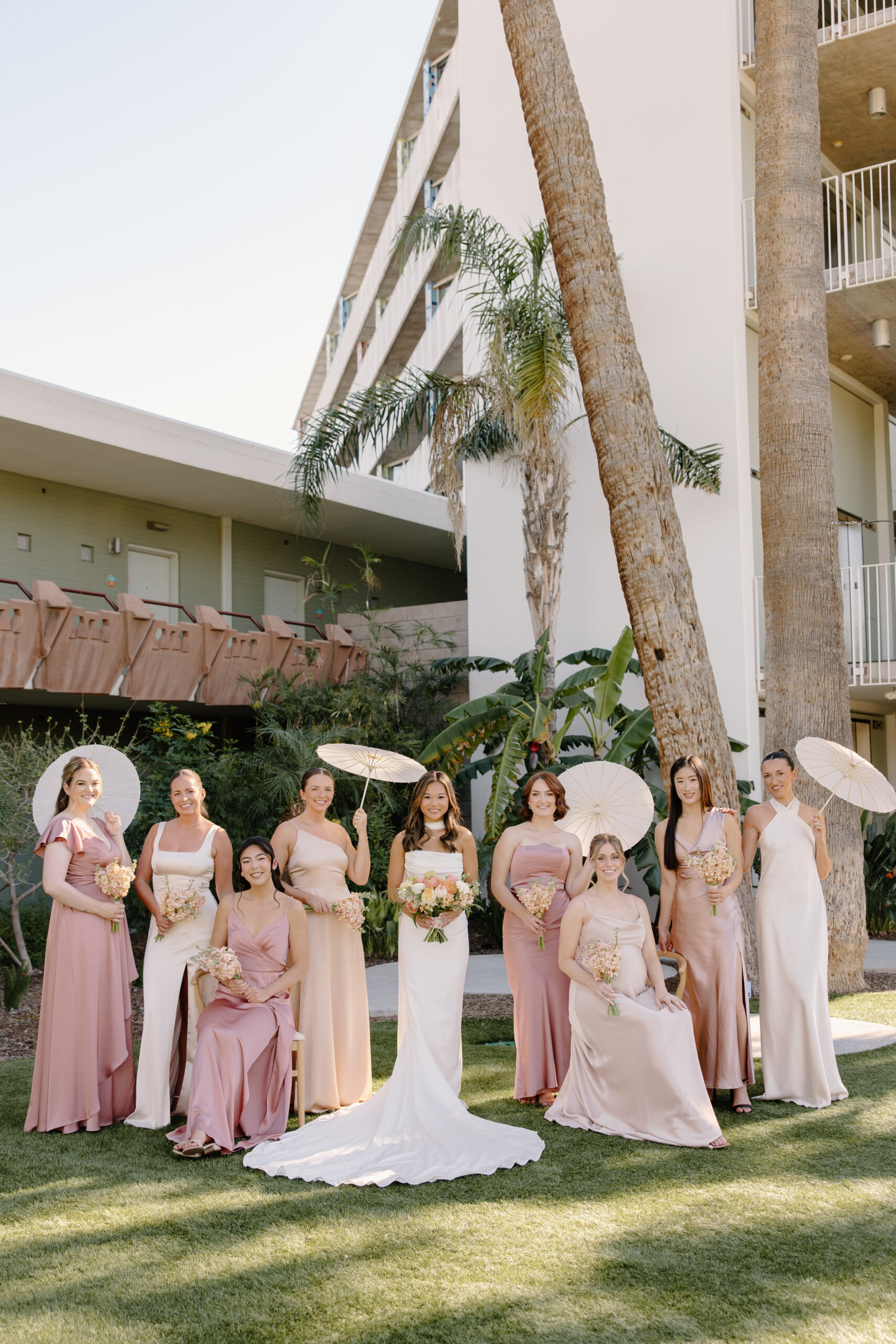 Bridesmaids and bride posing together outdoors in soft neutral and blush-toned dresses at Hotel Valley Ho
