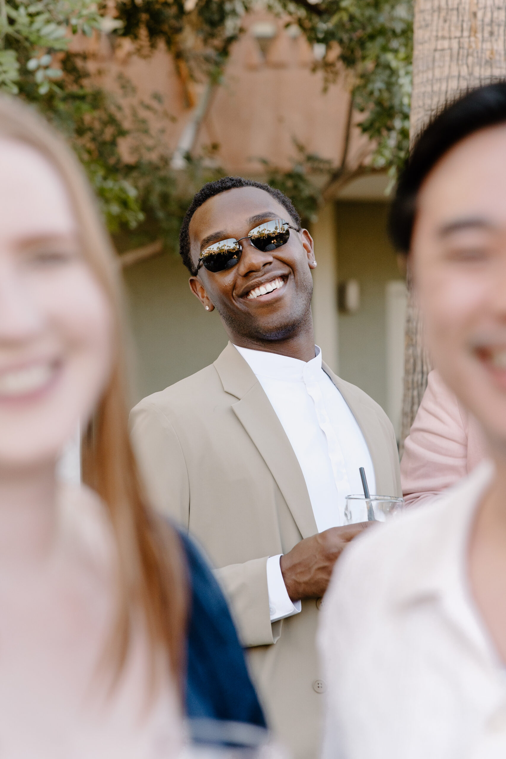 Guest smiling in sunglasses while holding a drink during an outdoor cocktail hour at Hotel Valley Ho