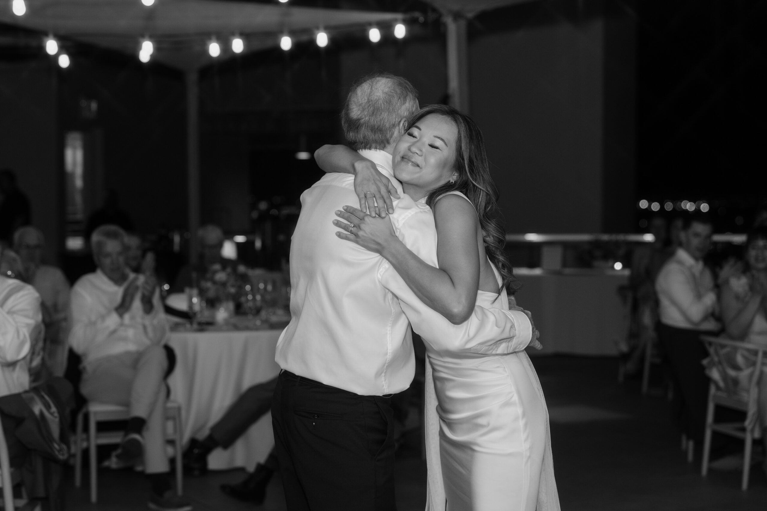 Black and white photo of bride hugging a guest during the reception, sharing an emotional moment