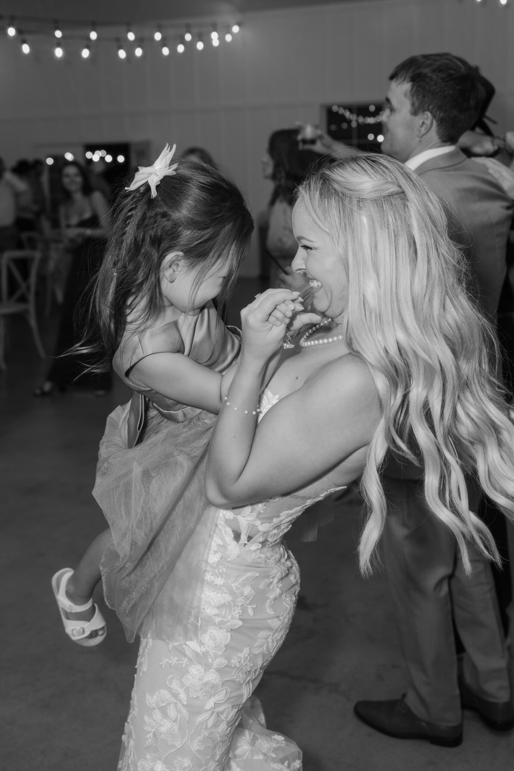 Black and white candid of the bride dancing with a young flower girl during the reception