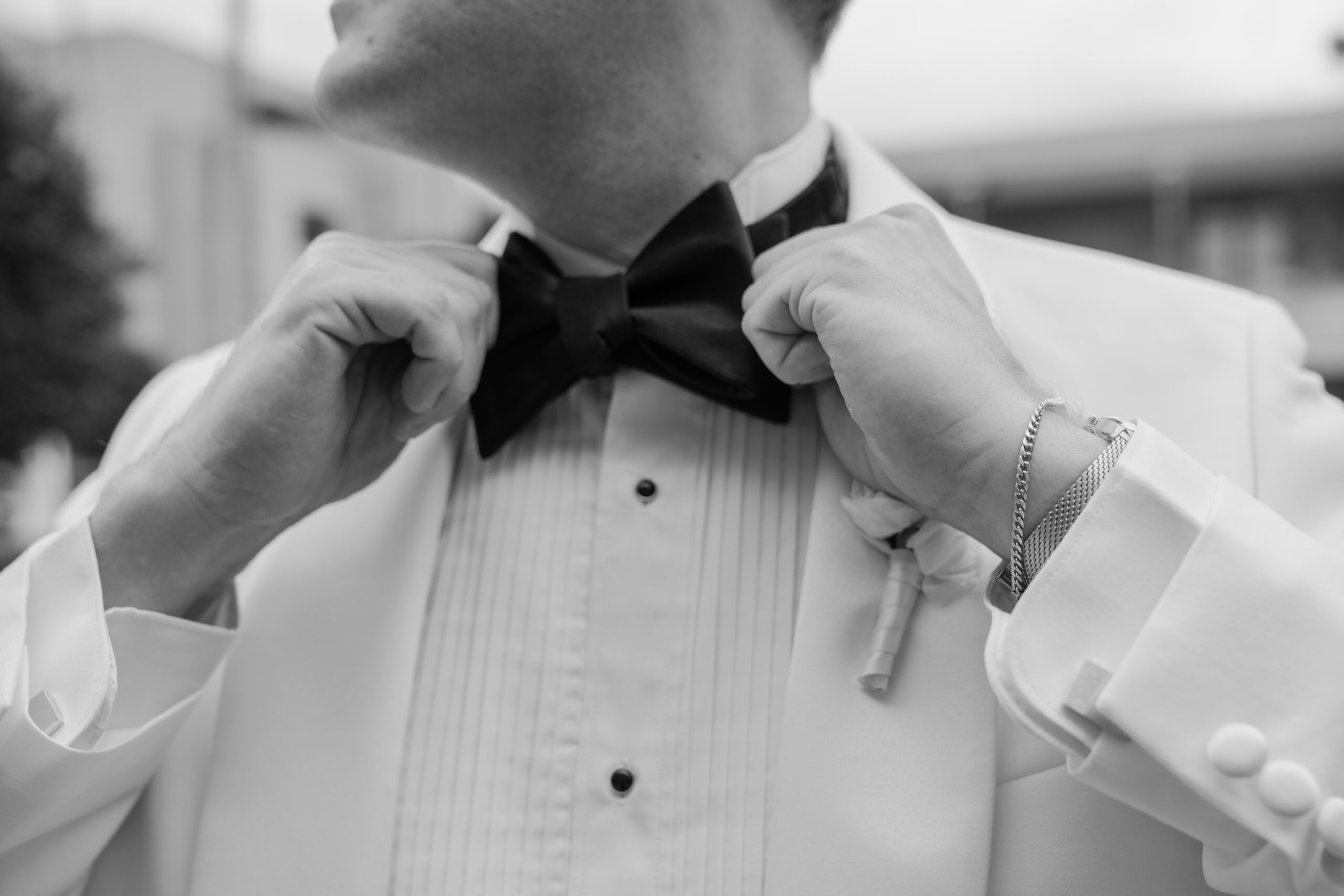 Black-and-white detail of the groom adjusting his bow tie before his Arizona Biltmore wedding.