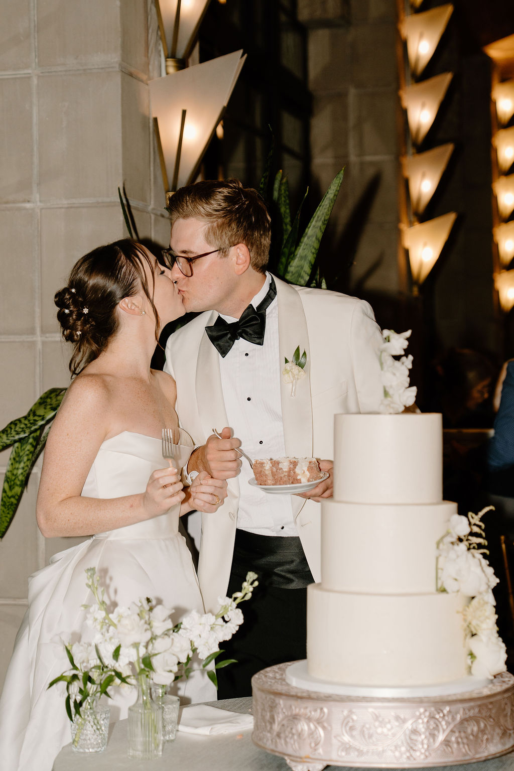 Bride and groom kissing beside their modern wedding cake during their Arizona Biltmore reception.