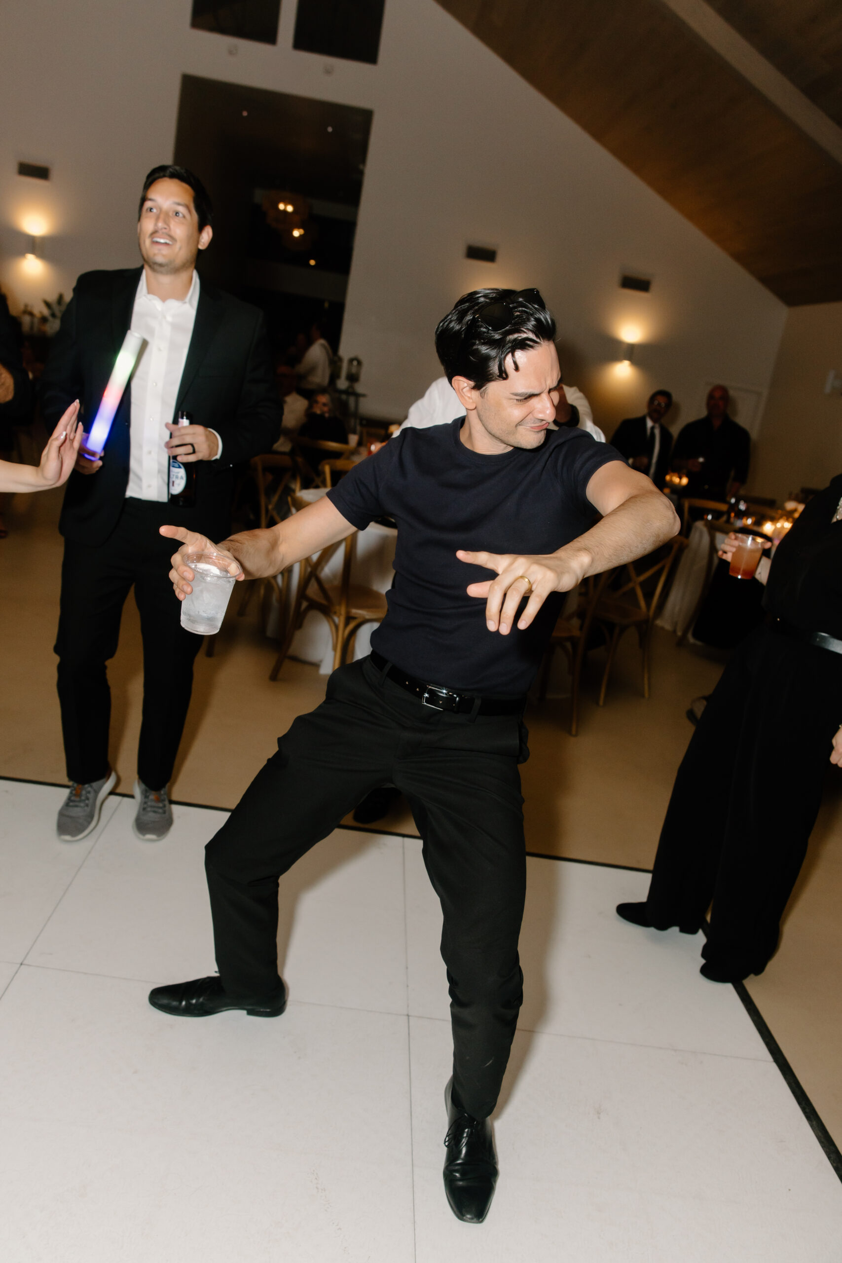 Candid photo of a wedding guest dancing with a drink in hand during the evening reception.